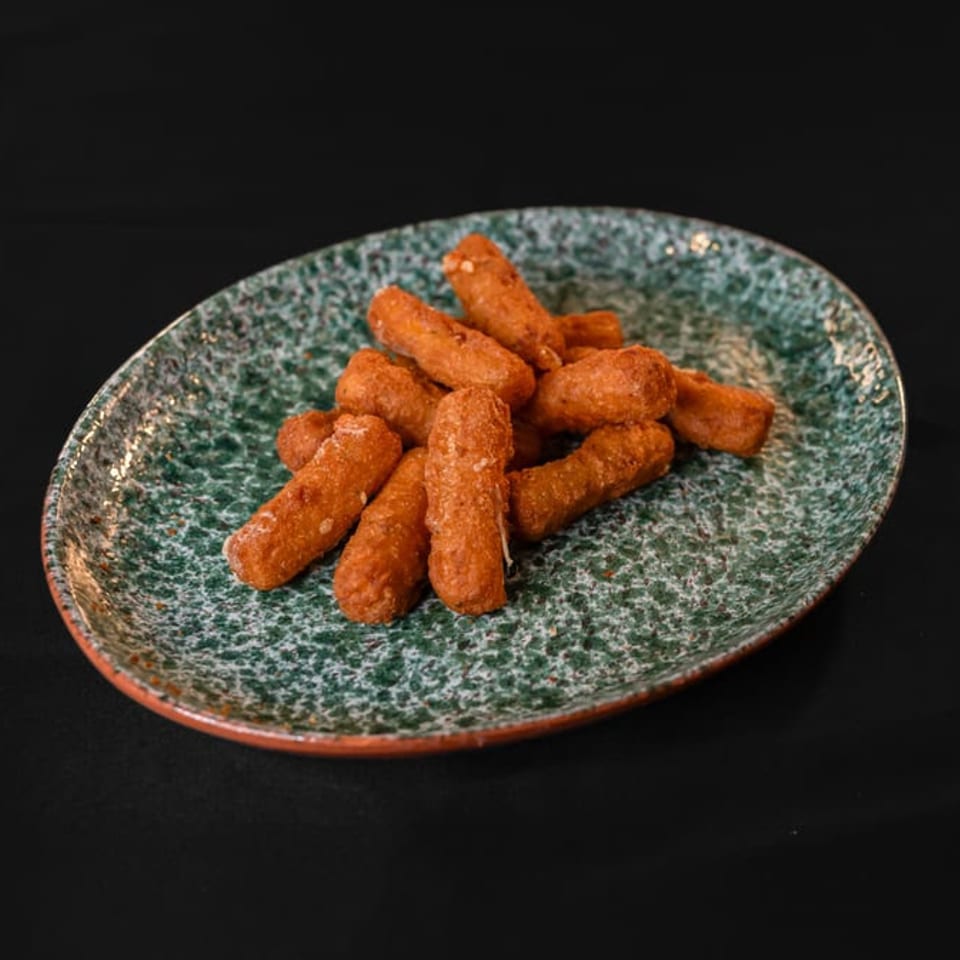 A green speckled oval plate filled with golden-brown fried mozzarella sticks on a dark background.