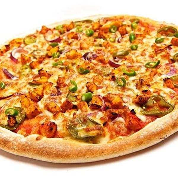 A whole chicken tikka pizza with red onions, green peppers, and melted cheese on a white background.